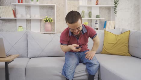 Happy-and-cheerful-young-dwarf-man-texting-by-phone-at-home.